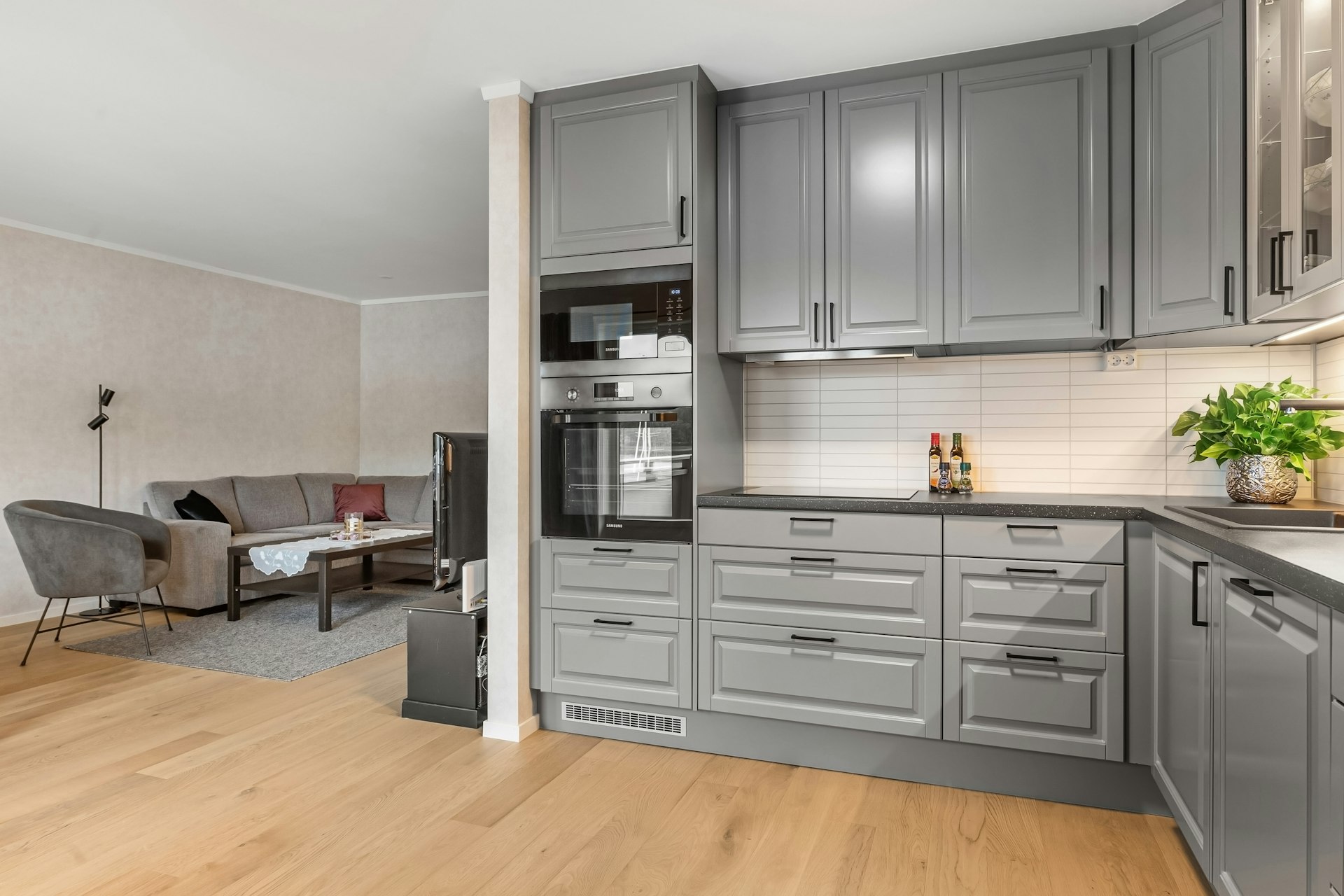 A large kitchen with a wooden floor and gray cabinets